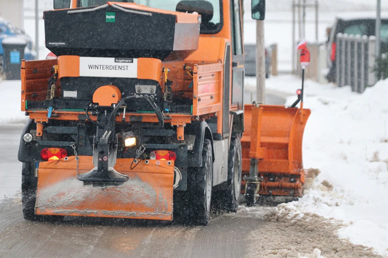 Ein oranger Schneepflug räumt eine verschneite Straße. — © Symbolbild